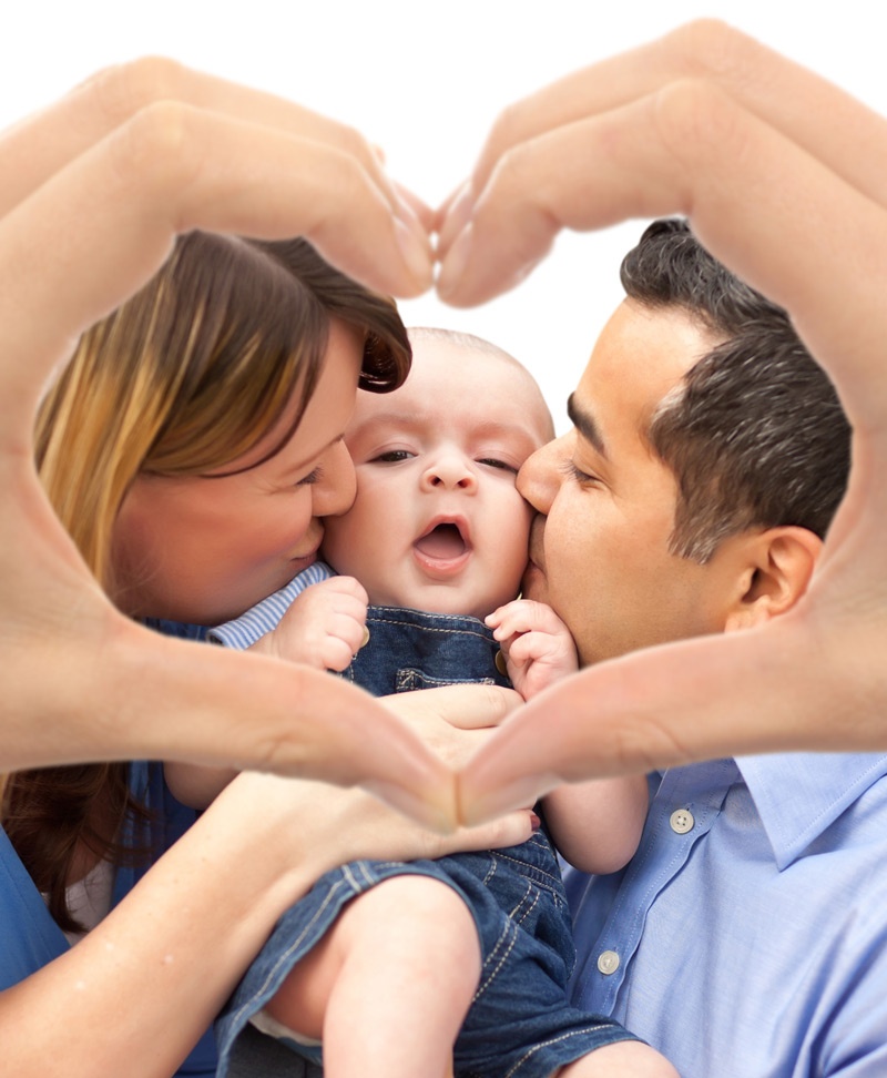 Parents kissing their baby, framed by hands making a heart shape.